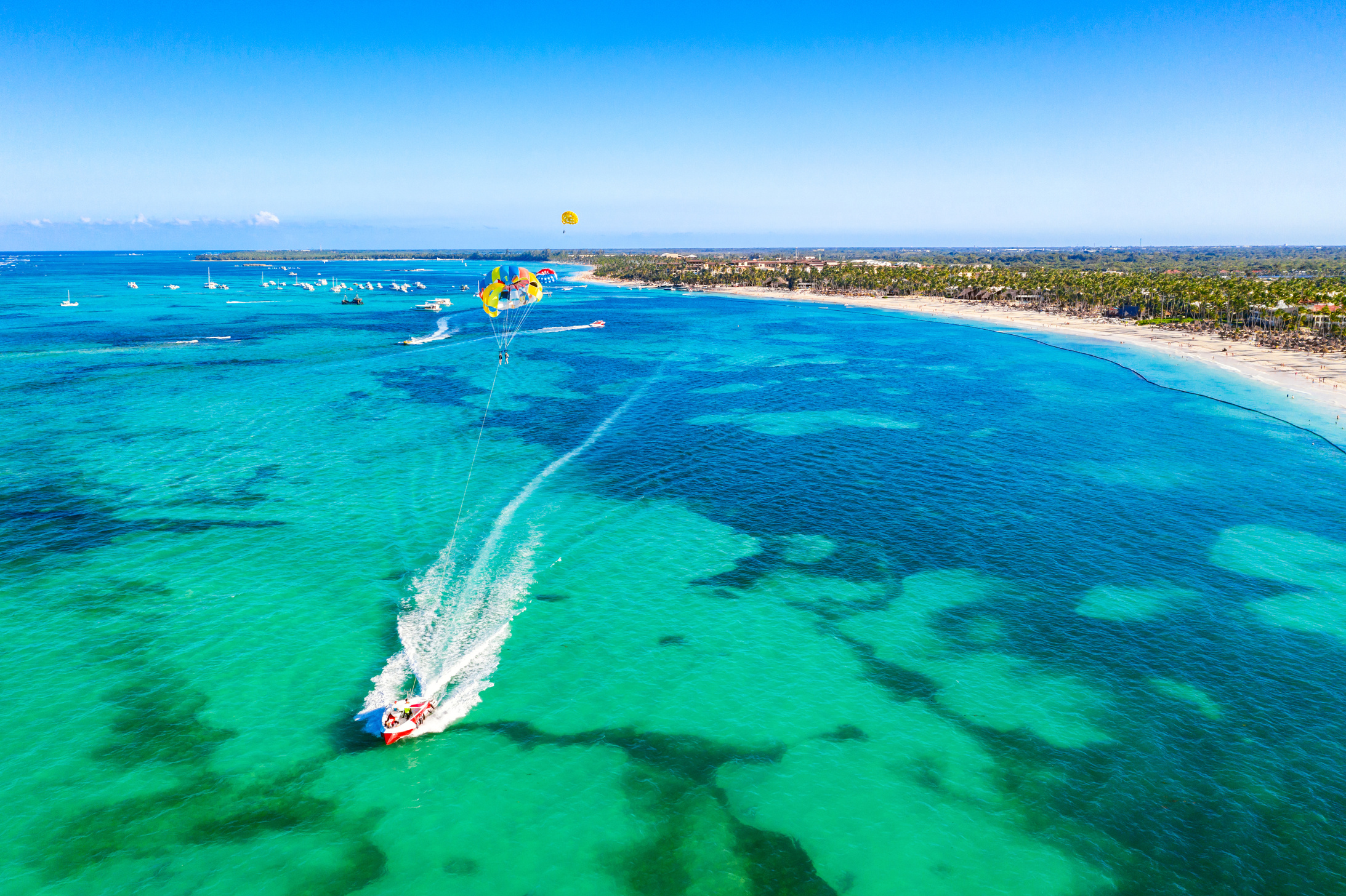 Tourists parasailing near Bavaro Beach, Punta Cana in Dominican Republic. Aerial view of tropical resort